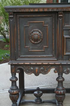 an ornately carved wooden cabinet sitting on top of a cement floor next to a sidewalk