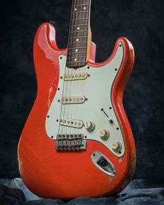 an old red electric guitar sitting on top of a table