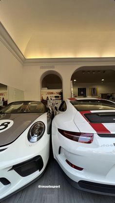 two white sports cars parked in a showroom