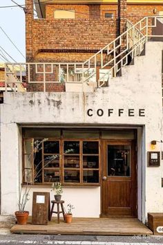 the outside of a coffee shop with stairs leading up to it's doors and windows