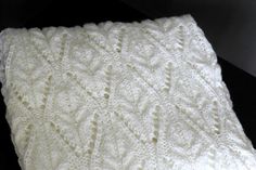 a white knitted blanket sitting on top of a black table