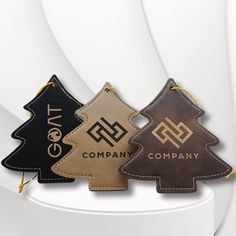 three leather christmas trees are shown on a white stand with gold trim and black lettering