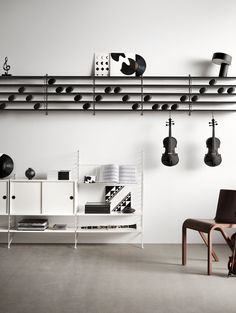 a white room with black and white objects hanging on the wall, two chairs in front of it