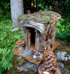 a fairy house made out of wood and mossy branches with mushrooms on the roof