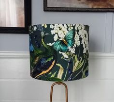 a lamp with a green, blue and yellow shade on it next to a painting