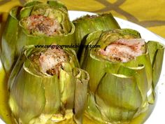 some artichokes are sitting on a white plate with mustard and seasoning