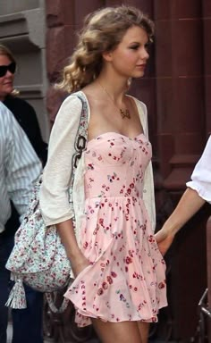 a woman in a pink dress is walking down the street with her hand on her hip