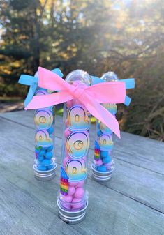 three glass vases with candy wrapped in pink and blue ribbons on a wooden table