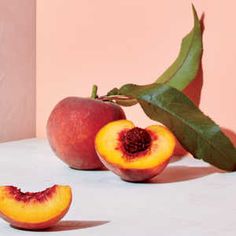 two peaches with one cut in half sitting on a table