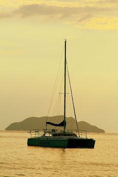 a sailboat floating in the ocean at sunset