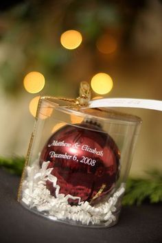 a red ornament in a clear box on top of a table with lights behind it