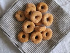 a bunch of doughnuts sitting on top of a cloth next to a spoon