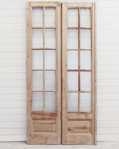 an old pair of double doors with glass panels on the front and back sides, against a white wall