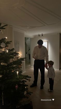 a man standing next to a little boy near a christmas tree