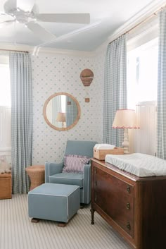 a baby's room with a blue chair, bed and dresser in the corner