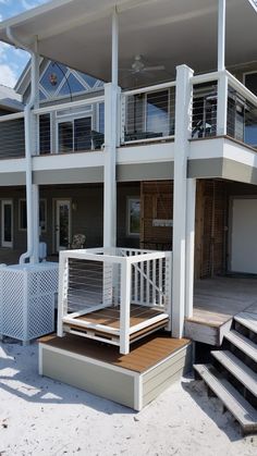 a white house with stairs leading to the second floor and another building in the background