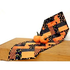 a wooden table topped with an orange and black piece of cloth next to pumpkins