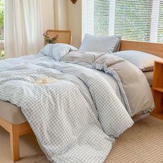 a bed with blue and white checkered comforter on it next to a window