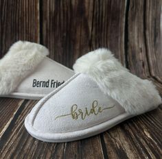 a pair of white slippers with the word bride written on them, sitting on a wooden surface