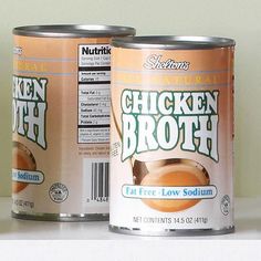 two cans of chicken broth sitting on top of a counter next to each other