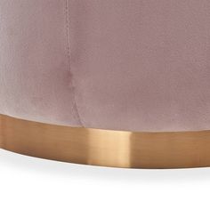 a pink velvet ottoman with gold trim