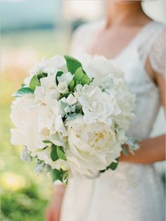 a woman holding a bouquet of white flowers