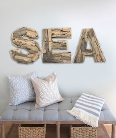 the word sea spelled in wood letters on a wall above a bench with pillows and blankets