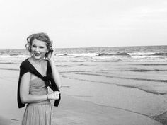 black and white photograph of woman on the beach talking on cell phone with waves in background