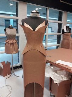 a dress made out of cardboard sitting on top of a table next to mannequins