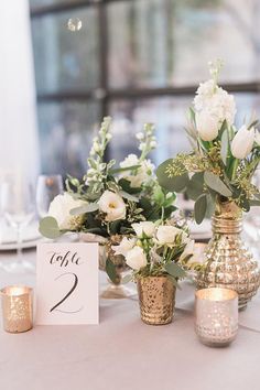 there are flowers in vases on the table at this wedding reception with candles and place cards