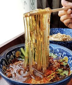 a bowl filled with soup and vegetables being stirred by a wooden spoon in the middle