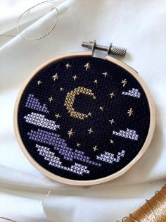 a cross stitch pattern with the letter c on it in gold and purple colors, surrounded by thread spools