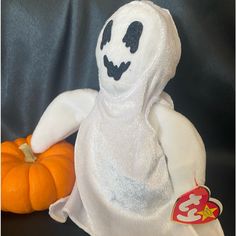 a white stuffed ghost next to an orange pumpkin