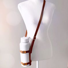 a white mannequin head with a brown leather strap around it's neck