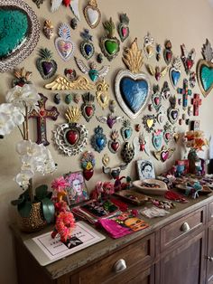 the wall is covered with many different pieces of art and decorations, including heart shaped brooches