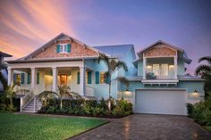 a house with blue siding and palm trees in the front yard at sunset or dawn