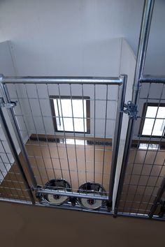 the inside of a jail cell with metal bars and wheels on each side, looking down at two windows