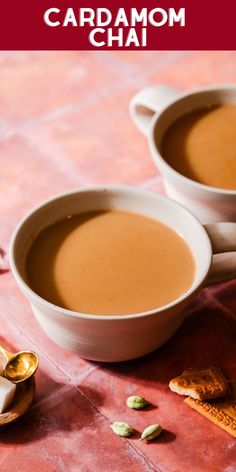 two cups of cardamom chai on a red tablecloth with spoons