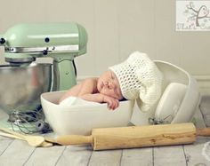 a baby laying in a bowl next to a mixer