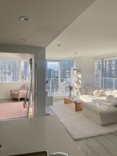 a living room filled with furniture and lots of windows overlooking the cityscape in the distance