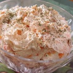 a glass bowl filled with mashed potatoes on top of a green and white table cloth