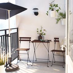 three wooden chairs sitting on top of a balcony next to a table with flowers in it