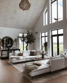 a living room filled with lots of furniture next to large windows and a chandelier