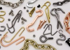 many different types of chains and hooks on a white surface with one metal hook in the middle