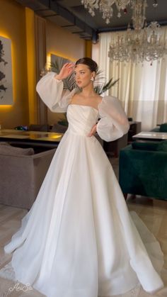 a woman in a white wedding dress posing for the camera with her hands on her head