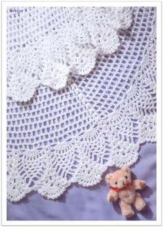 a teddy bear sitting on top of a white crocheted doily covered table cloth