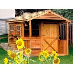 a small wooden shed with sunflowers in the yard