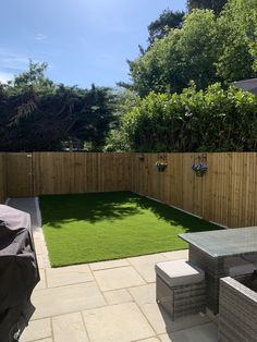 a small backyard with grass in the middle and an outdoor dining table on the other side