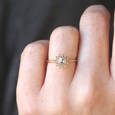 a woman's hand with a diamond ring on top of her finger, showing the center stone