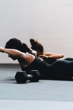 two women doing exercises with dumbbells on the floor in a dance studio or gym